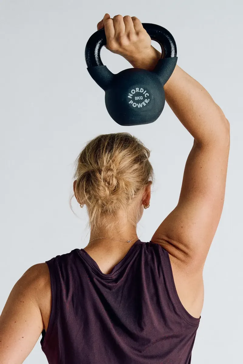 Kvinde presser kettlebell over hovedet