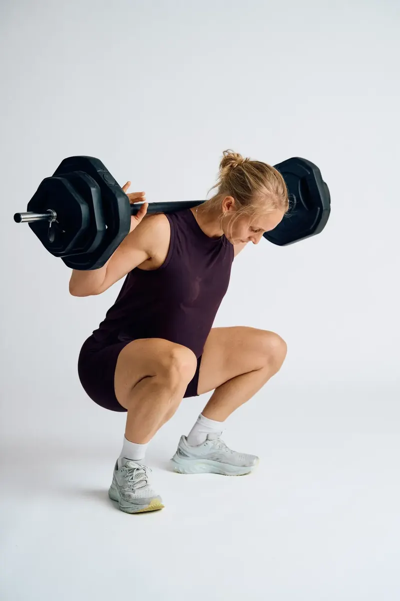 Kvinde laver squat med vægtstang