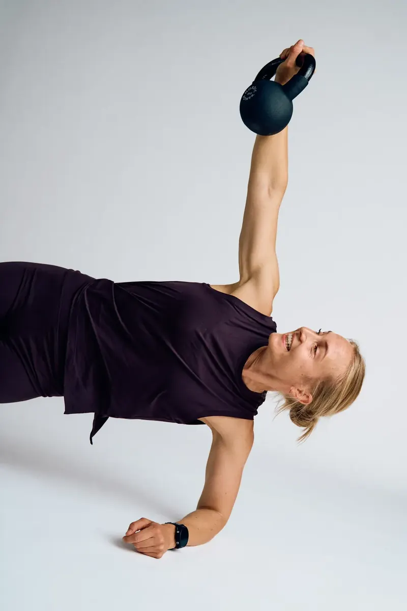 Kvinde med kettlebell strakt over hovedet fra liggende position